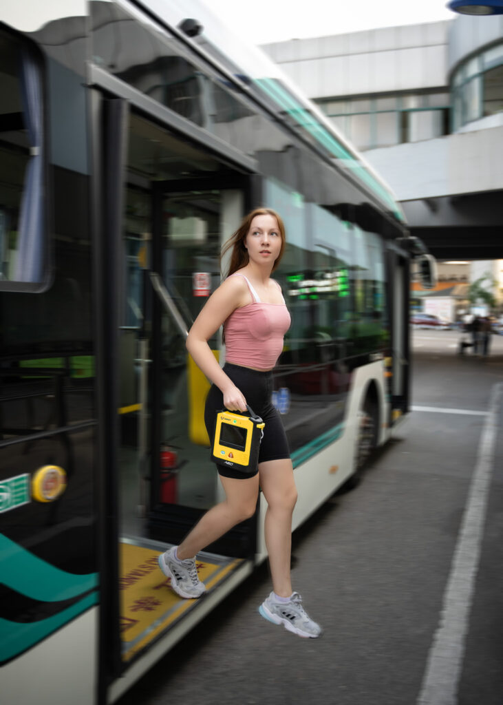 Kvinna kliver av buss med hjärtstartare i hand