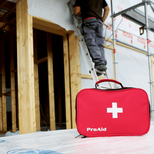 Förbandsväska i förgrunden, snickare på stege i bakgrunden. Så väljer du rätt första hjälpen-väska