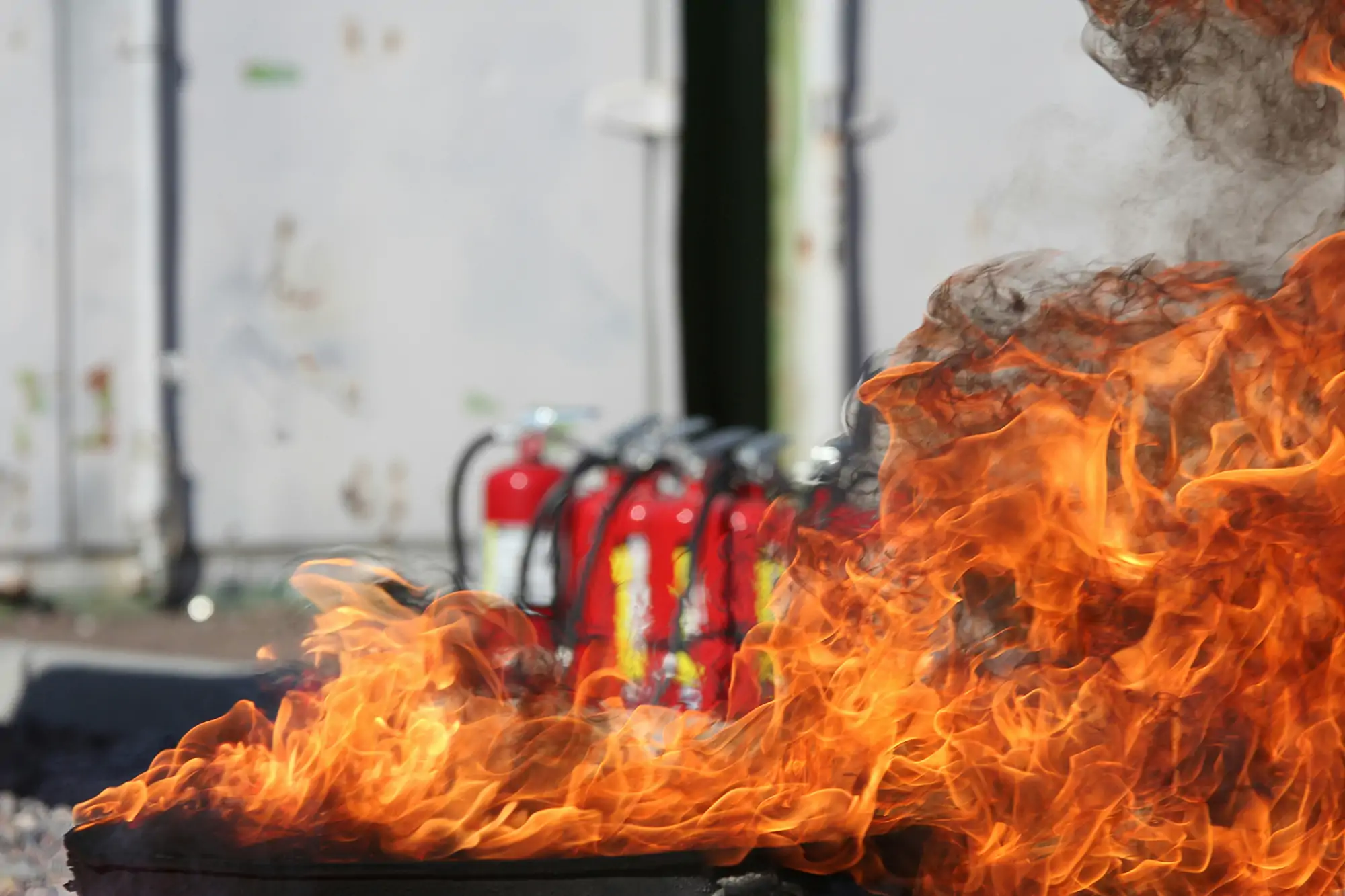 Eldsflammor med brandsläckare i bakgrunden