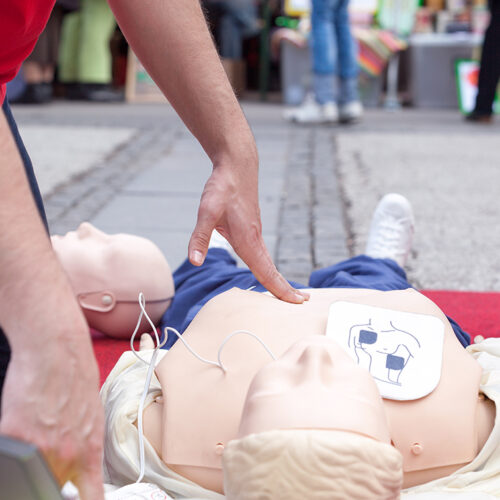 HLR-docka med övningselektroder fastsatta på bröstet. HLR för insatspersonal